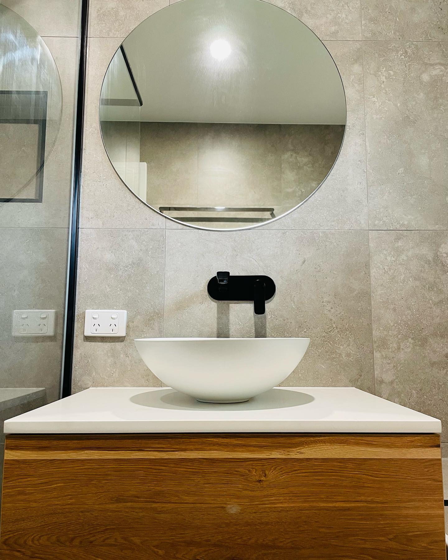 Round mirror over timber vanity with vessel basin