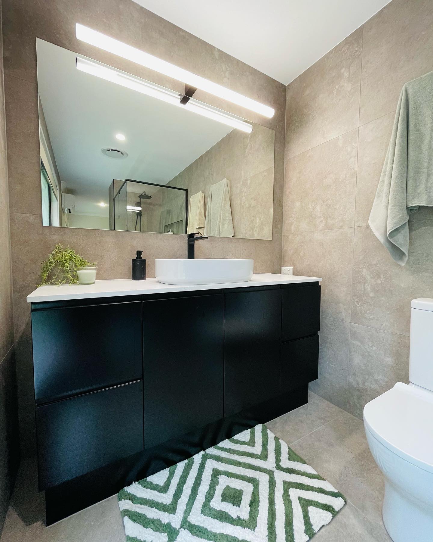 Black vanity with vessel basin and large mirror